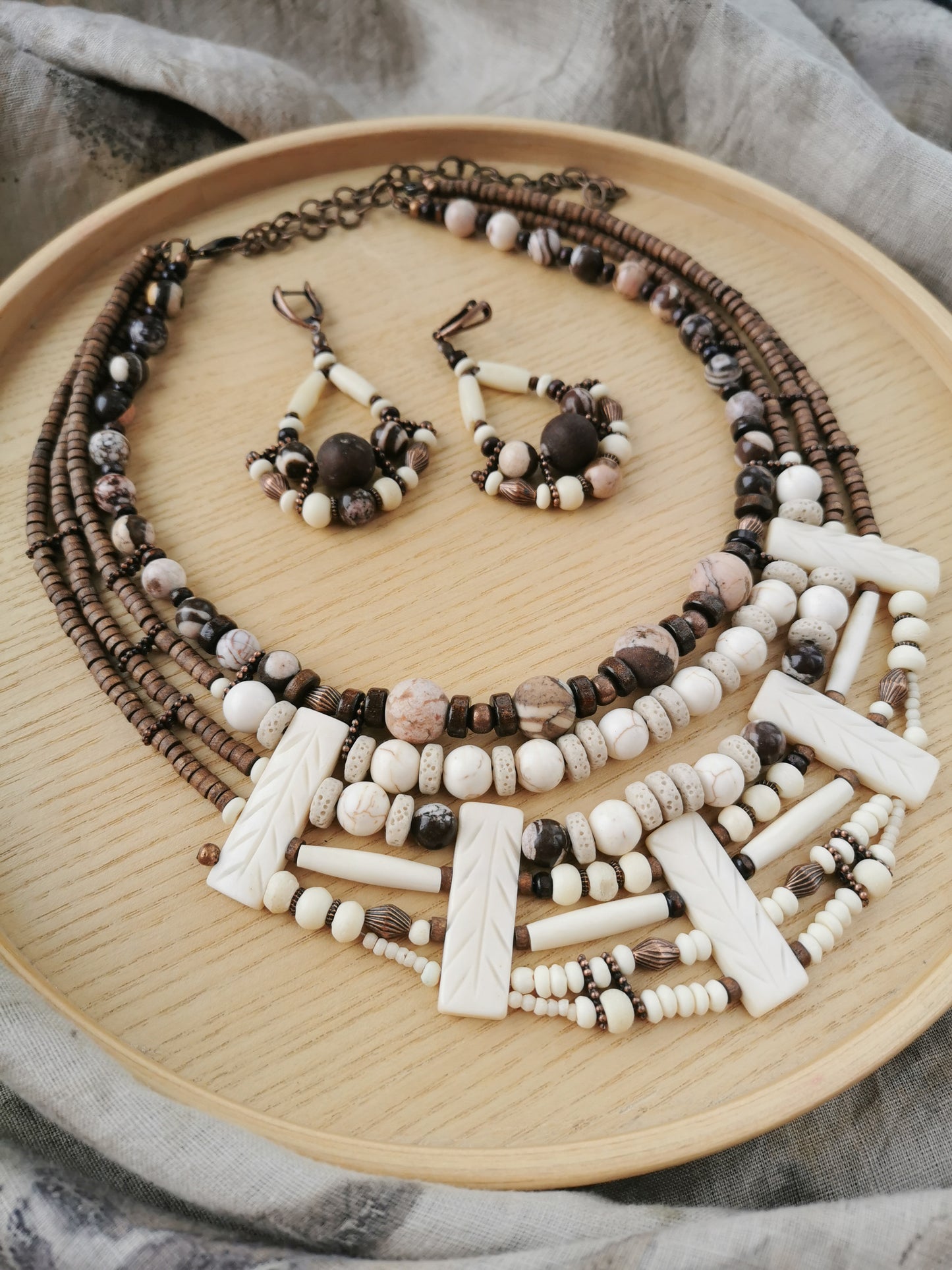 Beaded boho necklace and earrings set on a wooden plate
