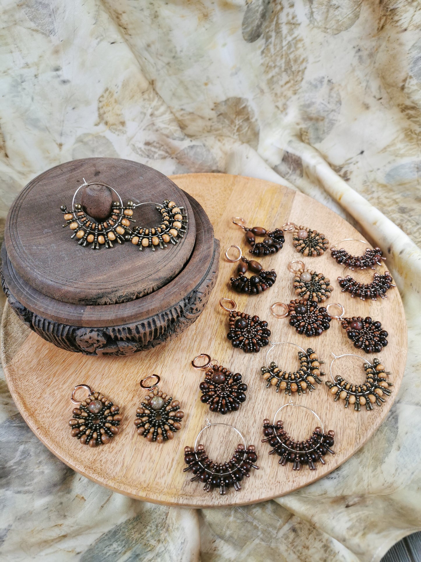 Collection of ornate earrings on a wooden tray with a textured background