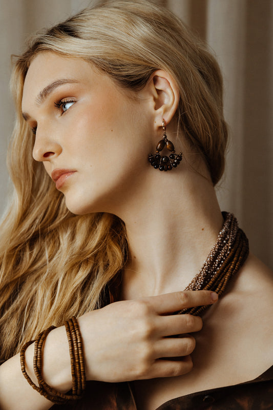 Woman wearing a beaded necklace and earrings with a neutral background