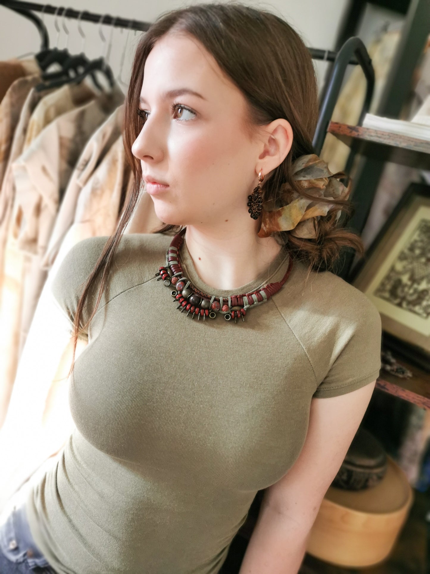 Woman wearing a green top with a decorative necklace in an indoor setting