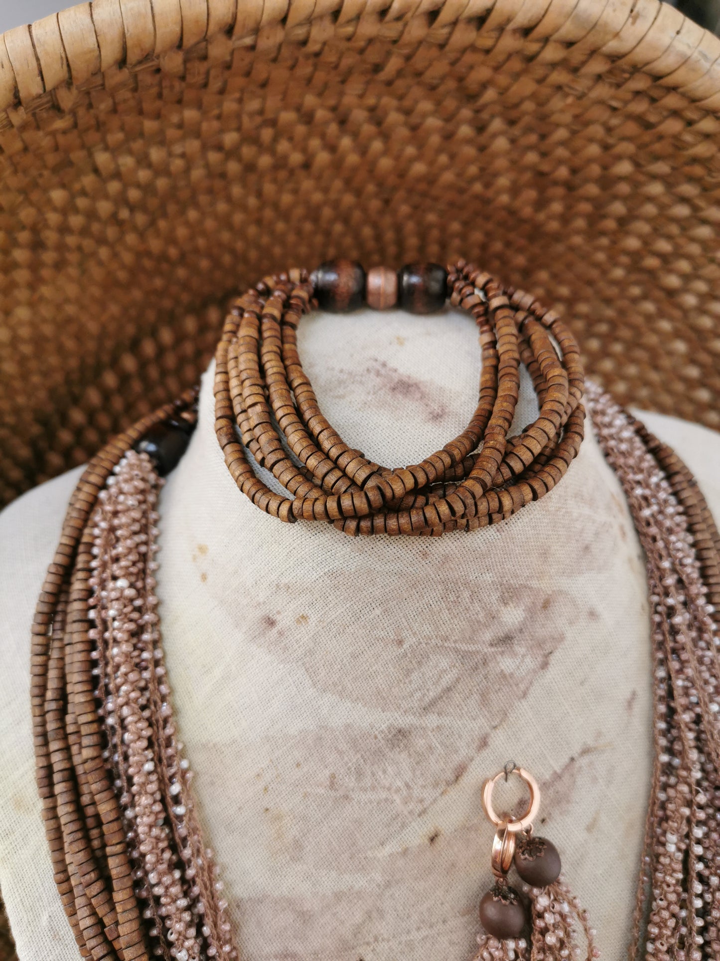 Brown beaded necklace on a marble surface with woven background
