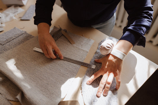 hands measuring fabric details on a table