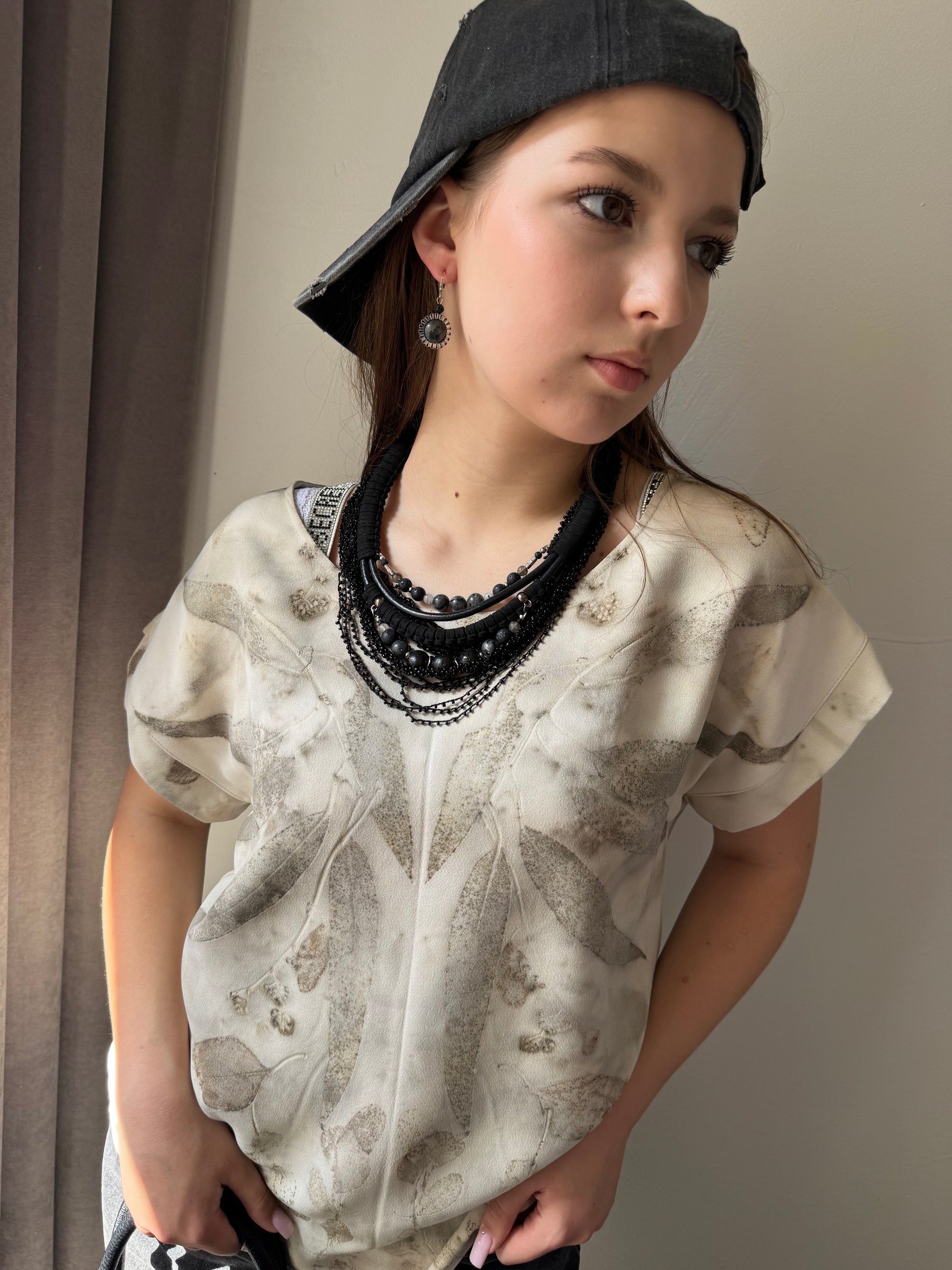 Person wearing a textured shirt and black cap indoors