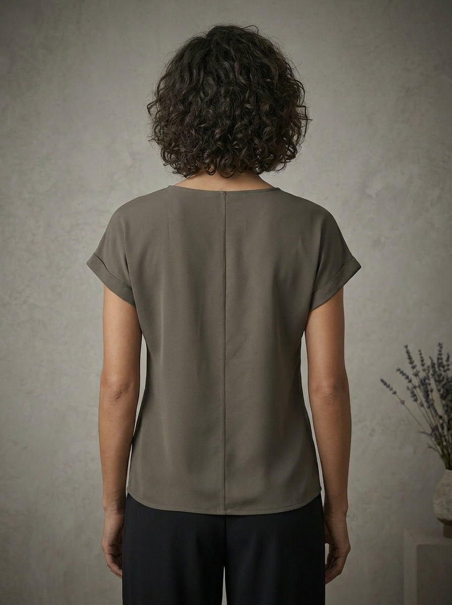 Person wearing a grey blouse against a neutral background