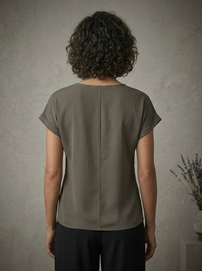Person wearing a grey blouse against a neutral background