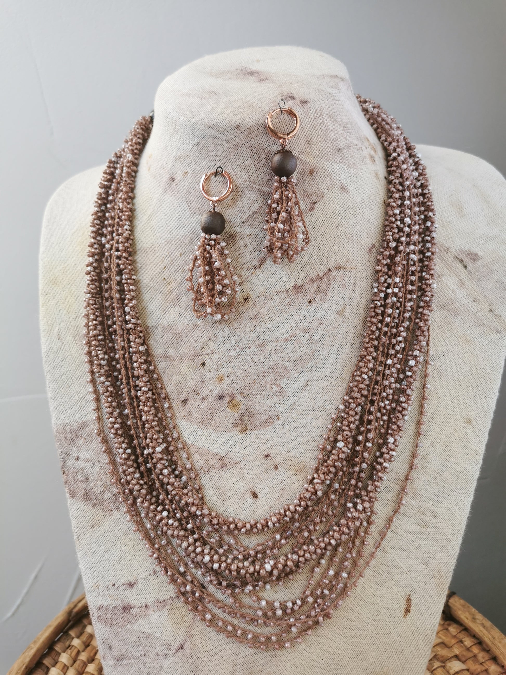 jewelry set of beige beads layering necklace and earrings on a display