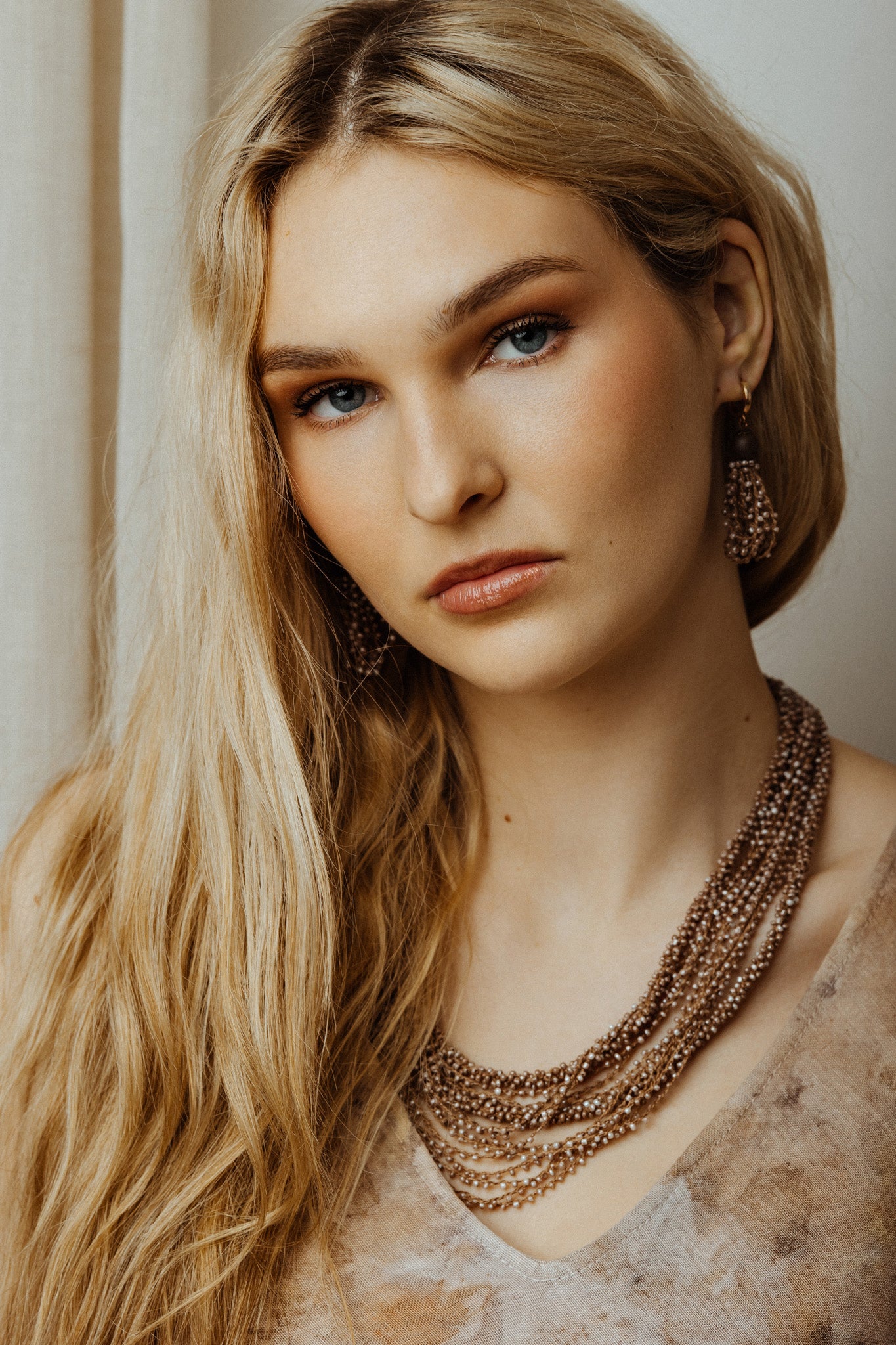 Woman wearing a beige string jewelry set with a neutral background