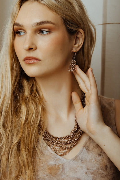 Woman wearing a beige string jewelry set with a neutral background