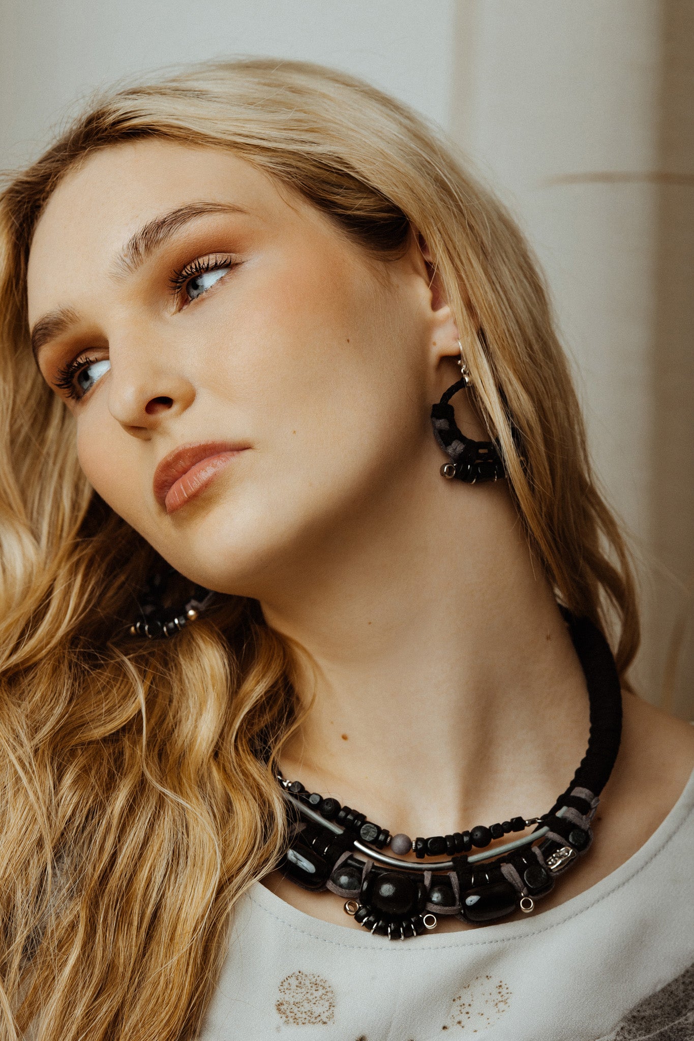 Woman wearing a black beaded necklace and earrings with a neutral background