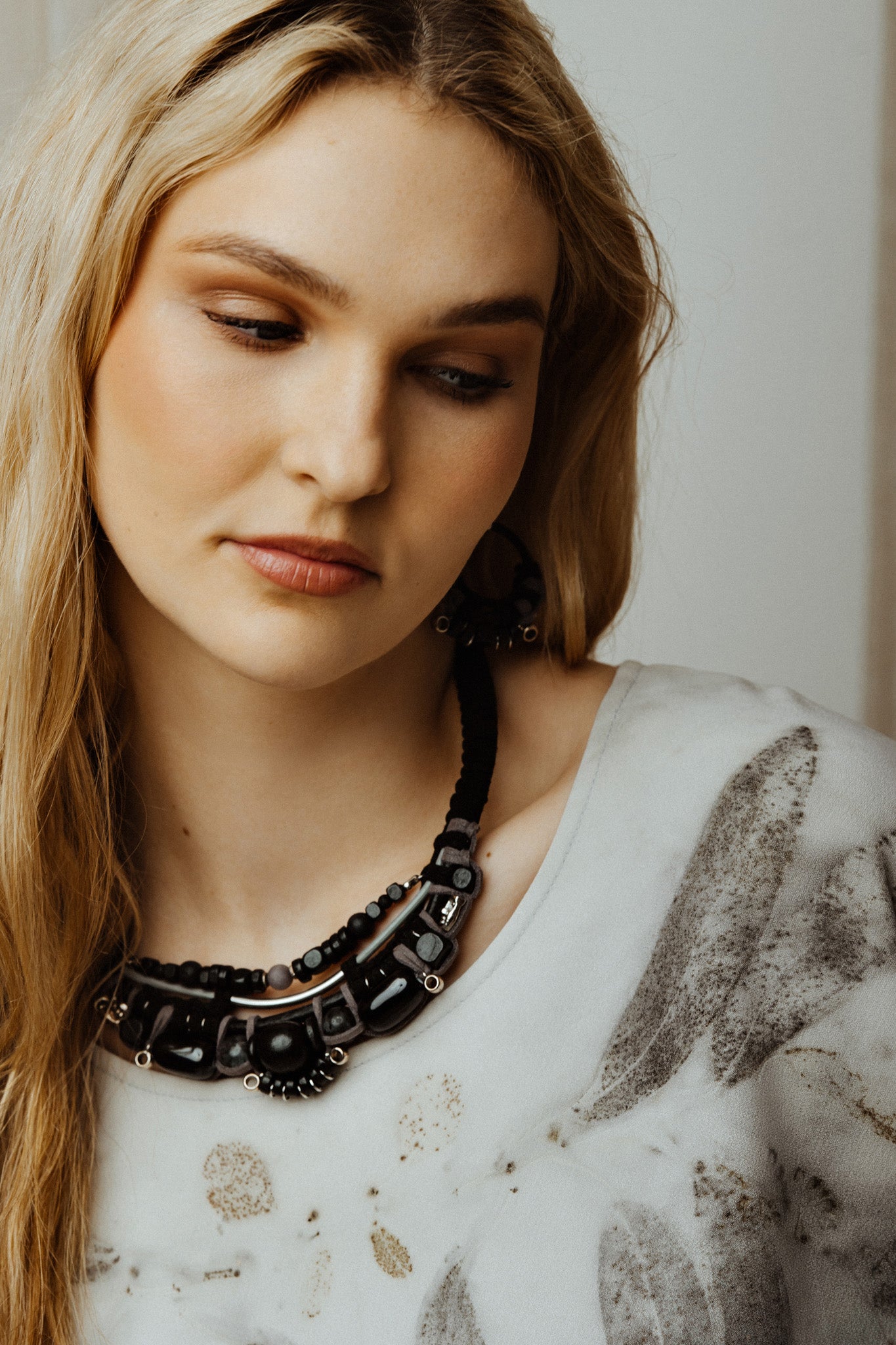 Woman wearing a black beaded necklace with a neutral background
