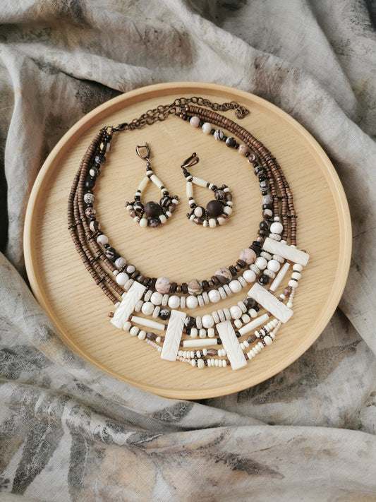 boho style Necklace and earrings set made of various beads on a wooden plate with a textured fabric background