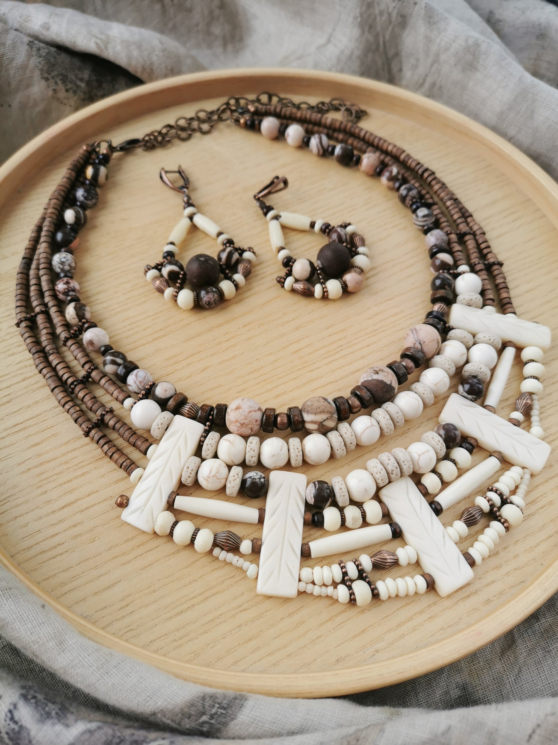 Beaded boho necklace and earrings set on a wooden plate