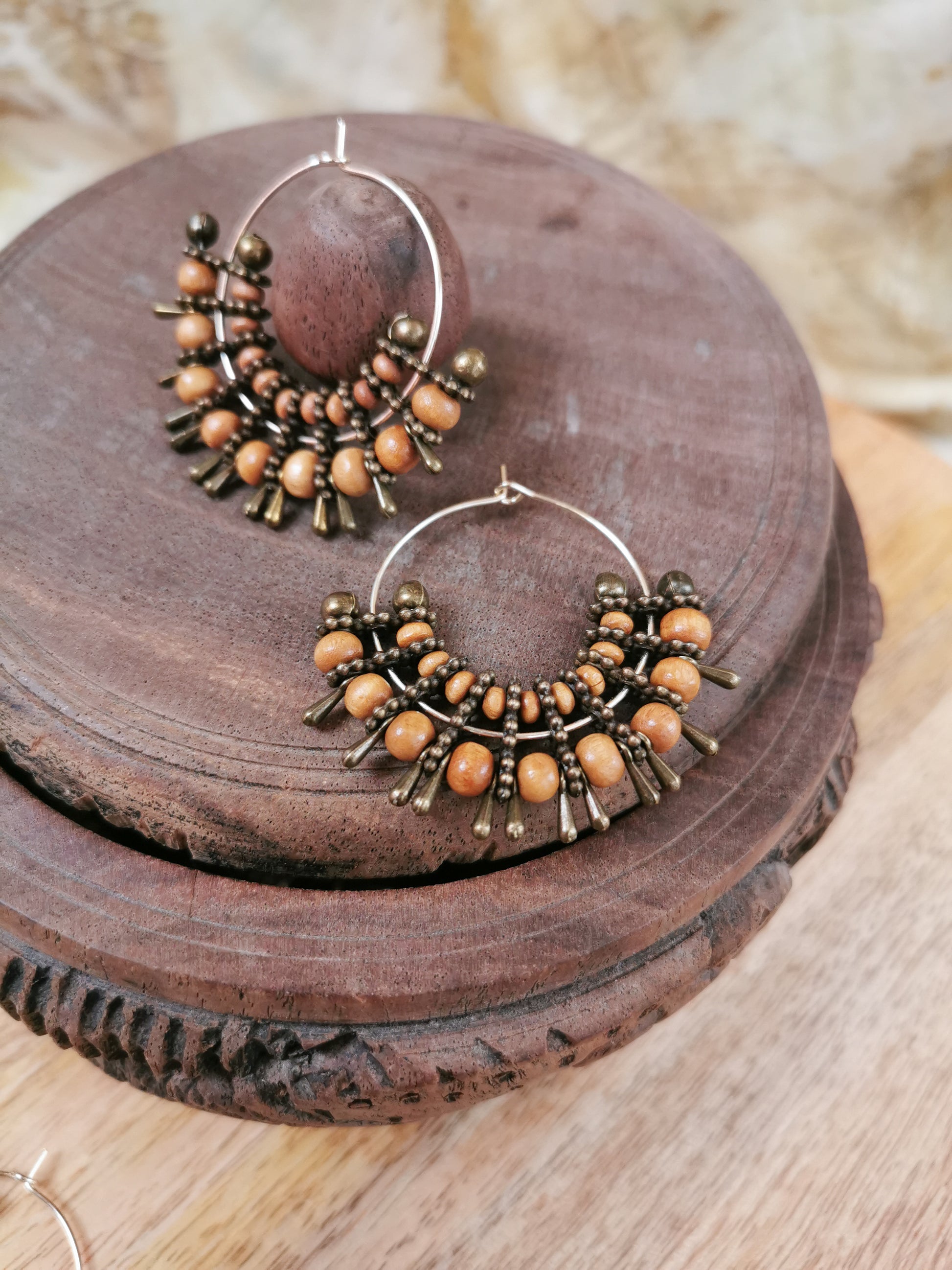 Pair of hoop earrings with brown beads on a wooden surface