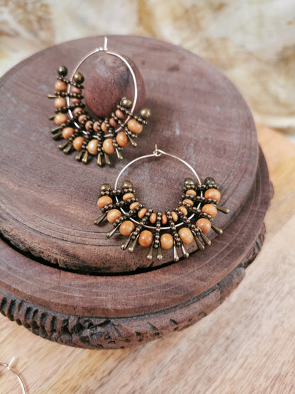 Pair of hoop earrings with brown beads on a wooden surface
