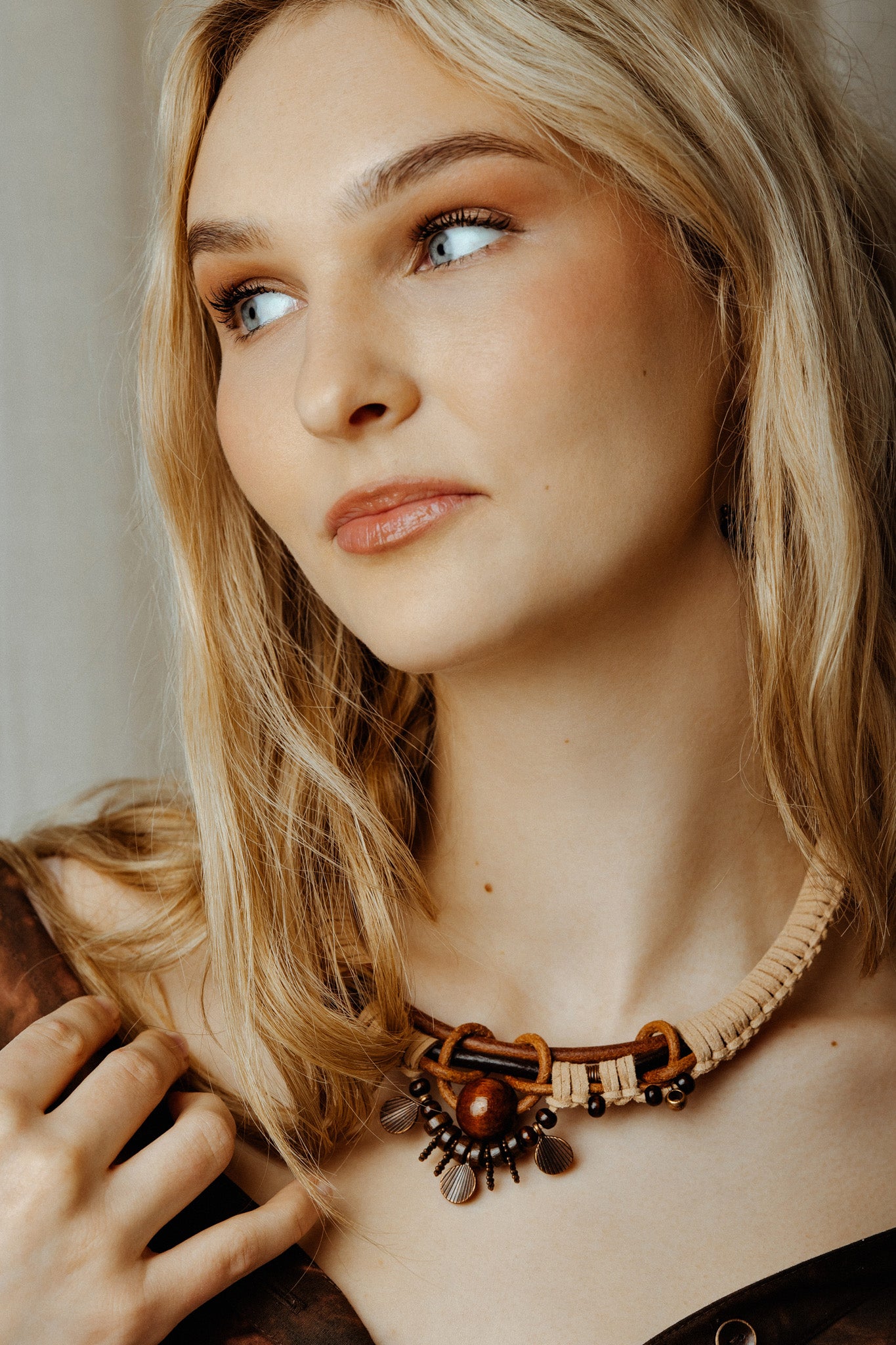 Woman wearing a boho goddess necklace with a neutral background