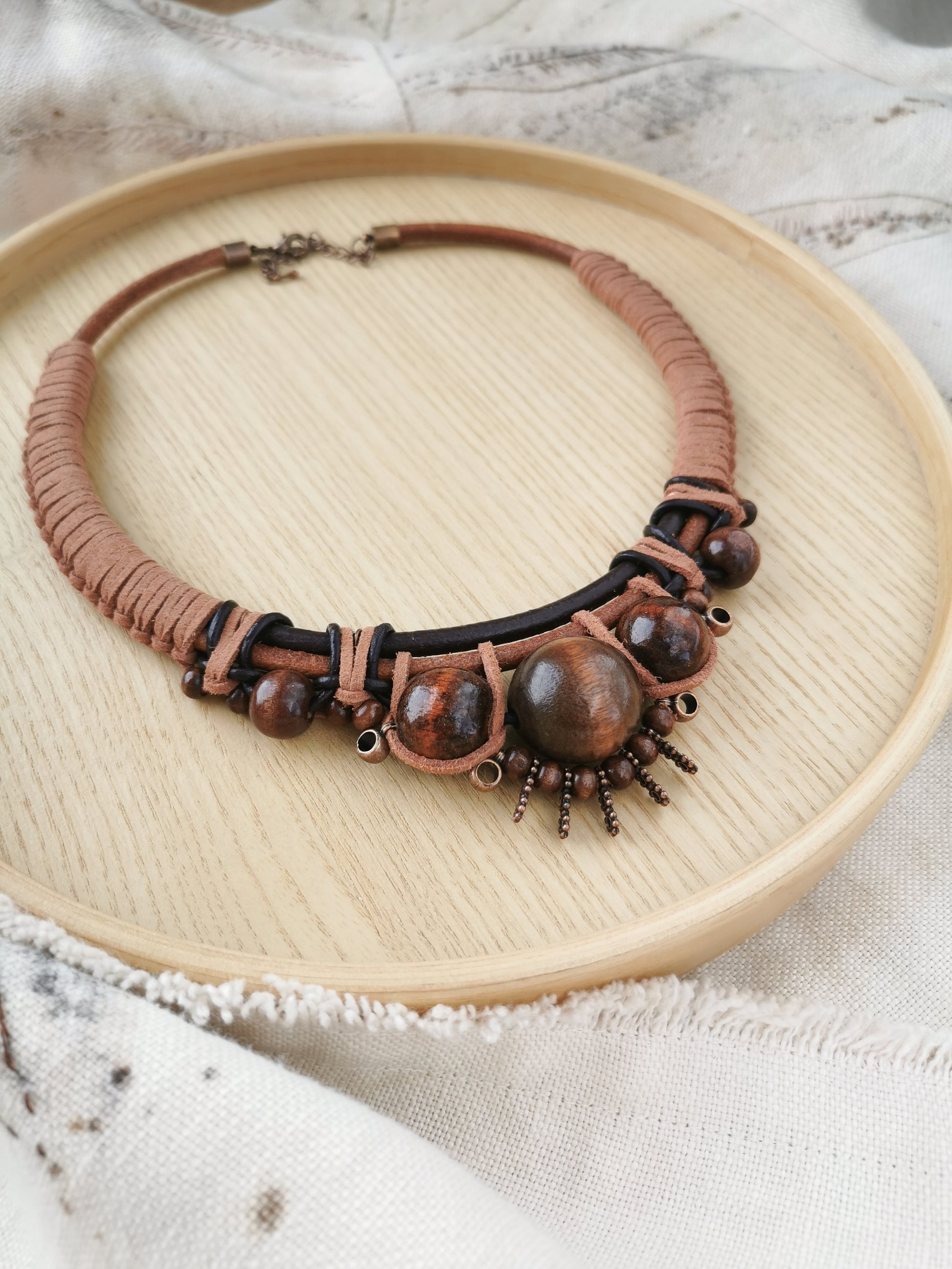 Brown boho beaded necklace on a wooden plate with a textured surface