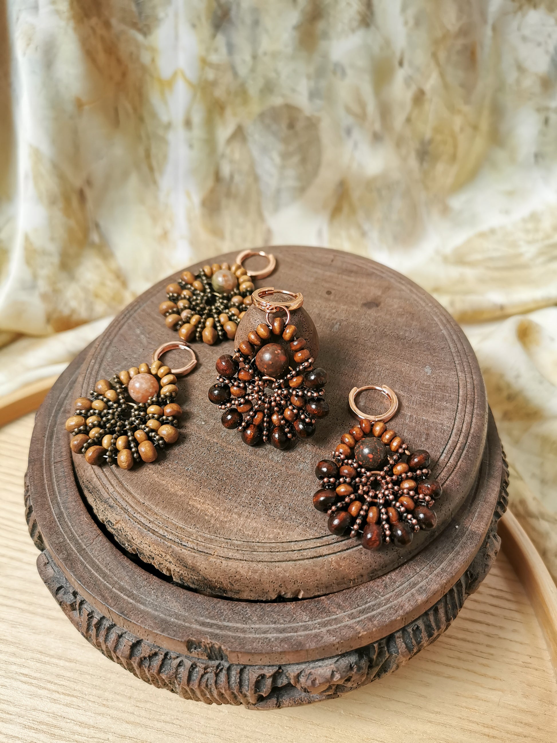 Set of beaded earrings on a wooden surface with a textured fabric background