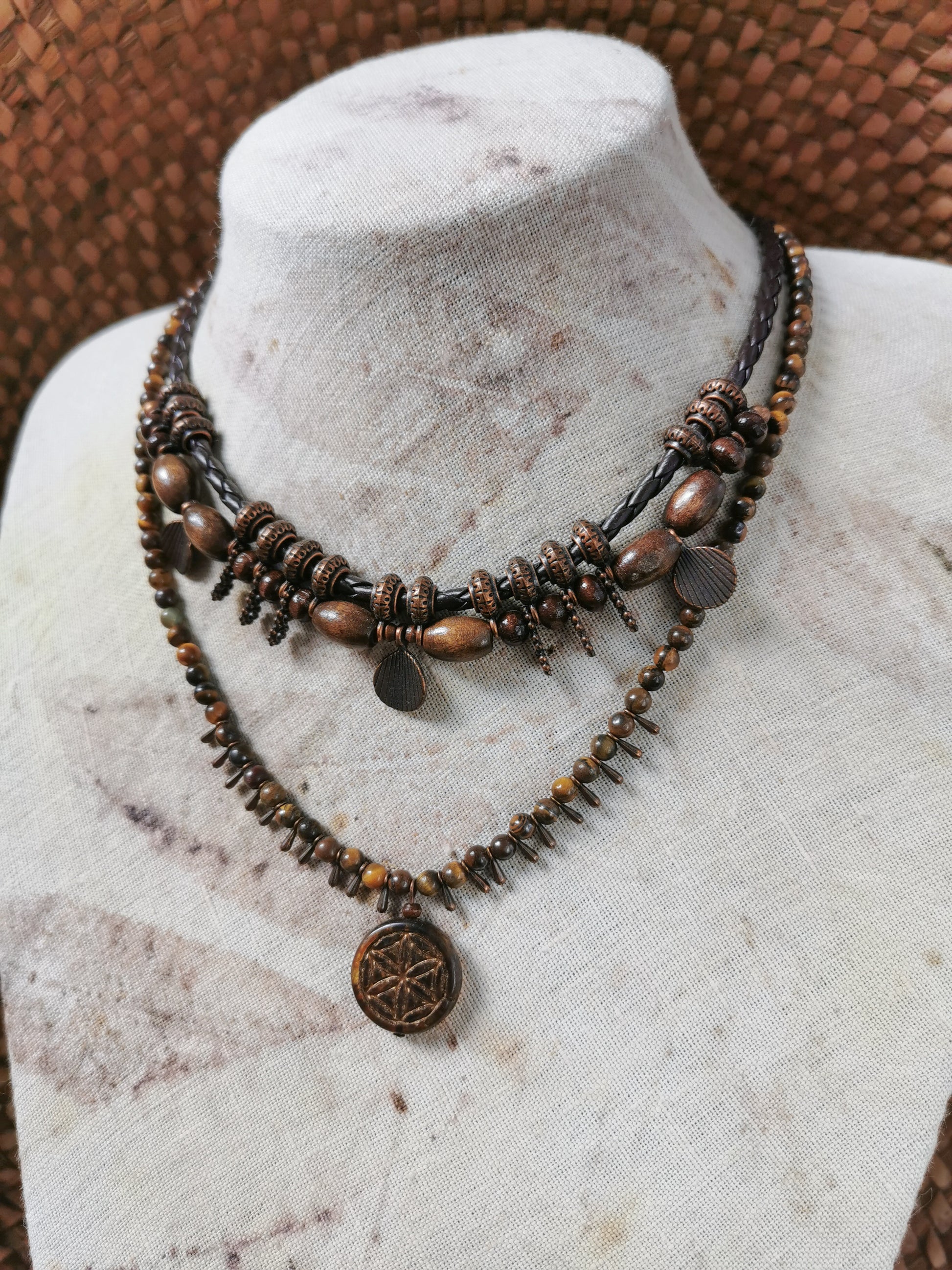 Layered necklace with brown beads and coins on a mannequin bust.