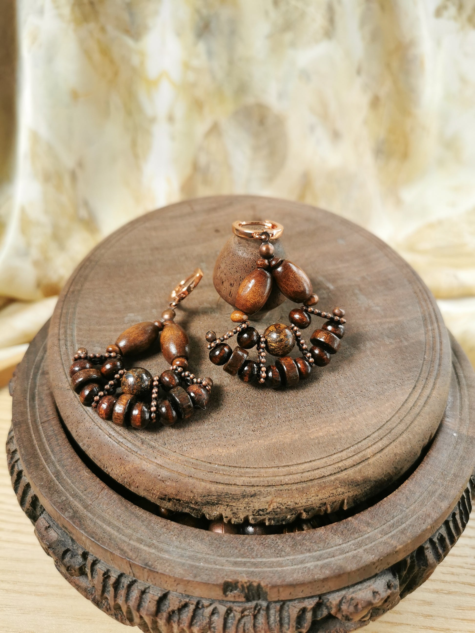 Pair of wooden earrings on a wooden stand with a textured background