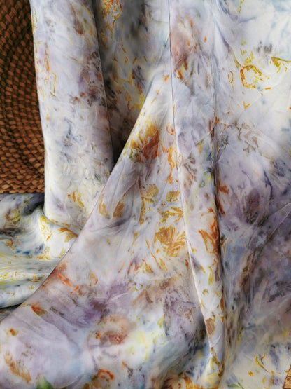 Close-up of patterned silk scarf with shades of white, gray, and orange.
