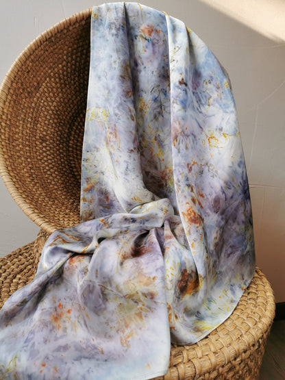 Colourful silk scarf draped over a woven chair against a neutral wall.