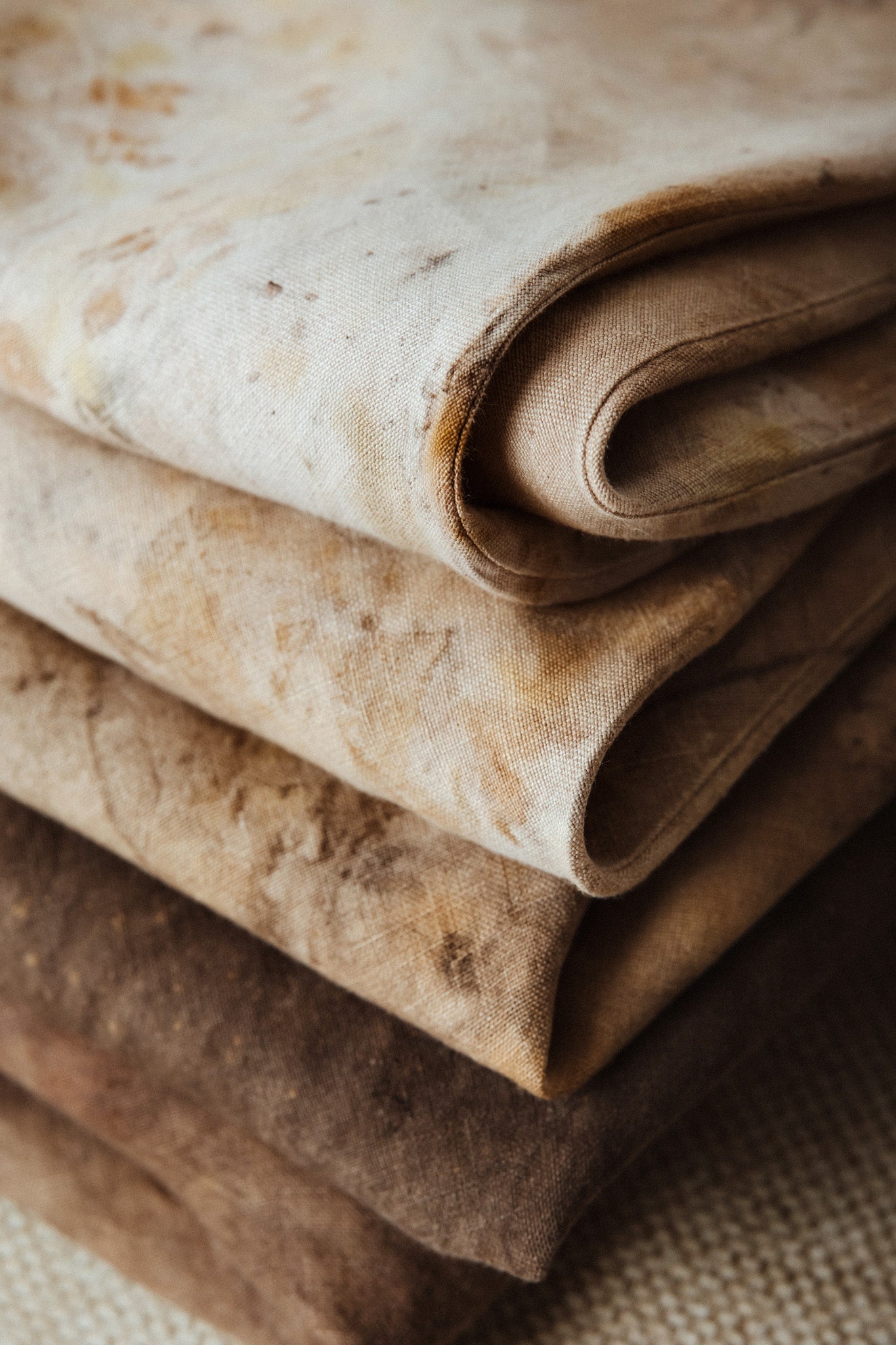 Stack of folded linen dresses on a textured surface