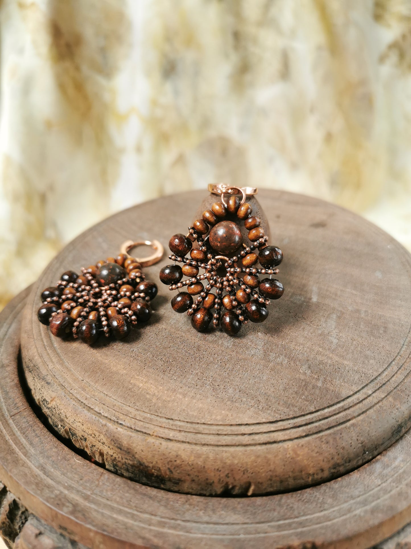 Pair of beaded earrings on a wooden surface with a blurred natural background