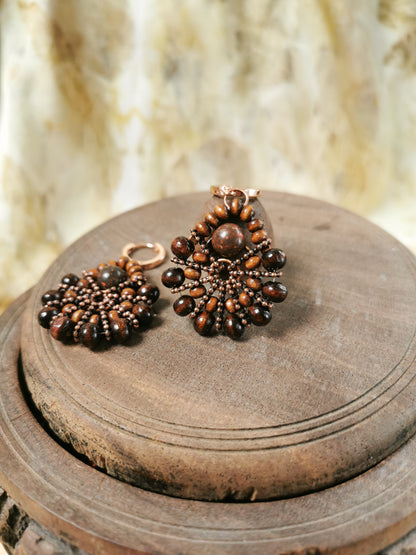 Pair of beaded earrings on a wooden surface with a blurred natural background