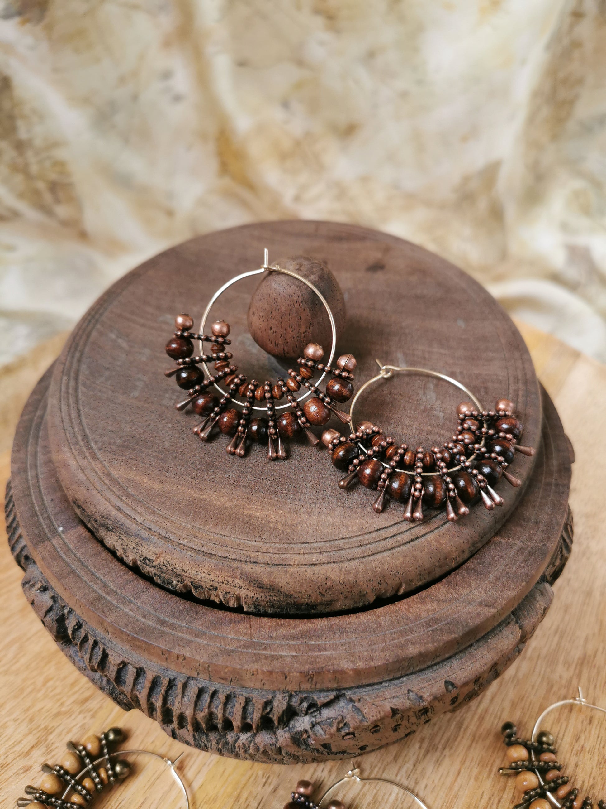 Pair of bronze hoop earrings with beads on a wooden surface