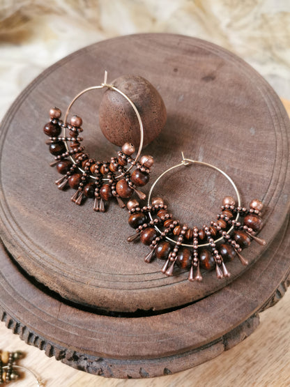 Pair of hoop boho earrings with bead details on a wooden surface