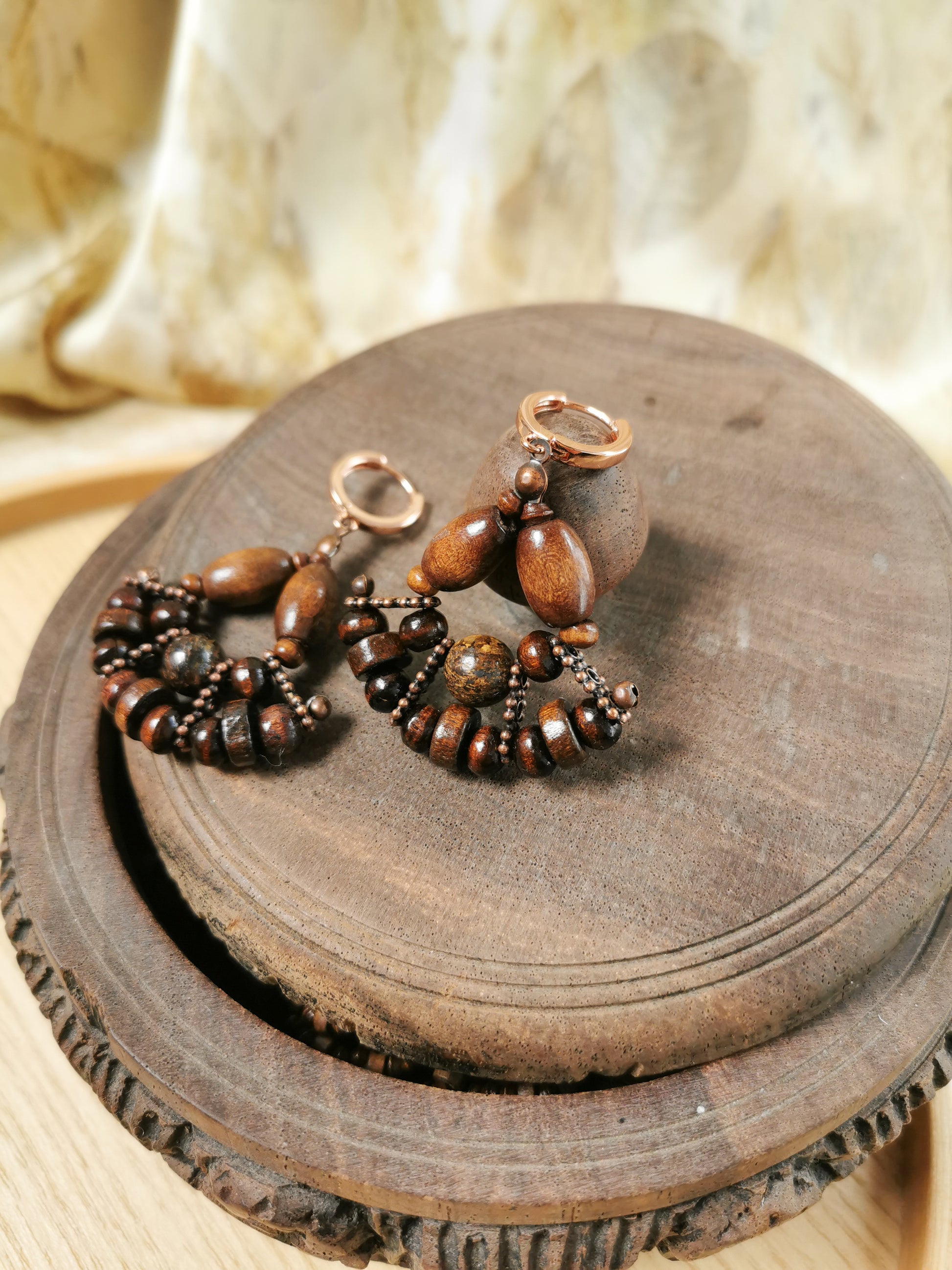 Pair of wooden beaded earrings on a wooden surface with a soft background