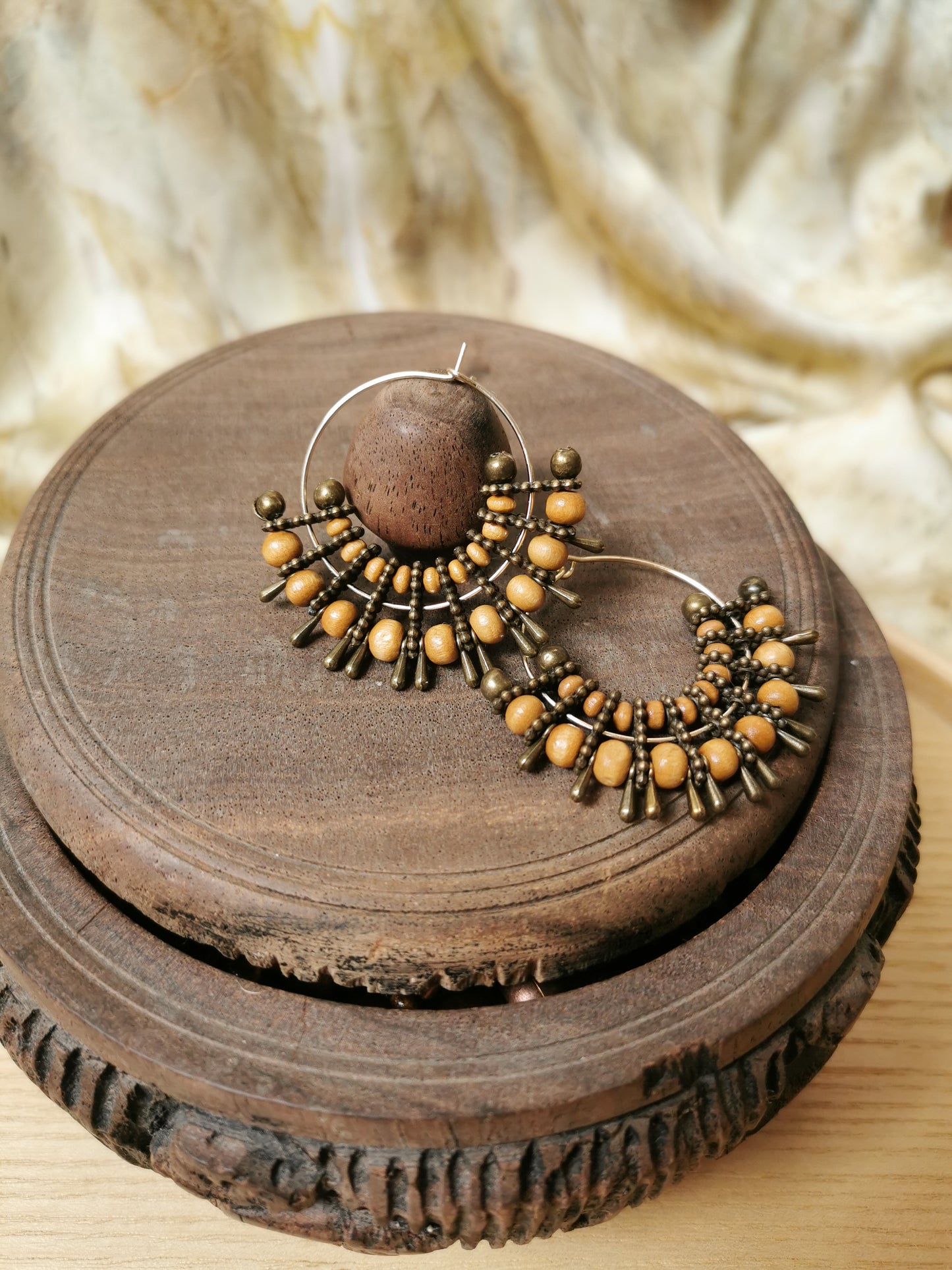boho beaded earring on a wooden surface with a textured background