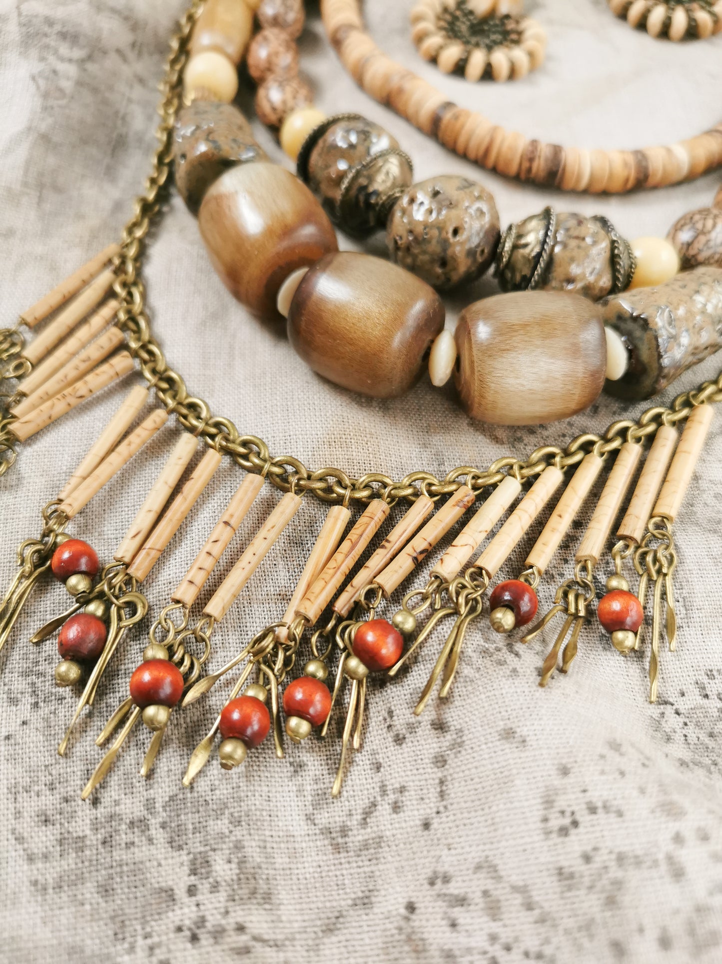 Necklace with wooden beads, coral-like stones, and brass chain on a textured surface