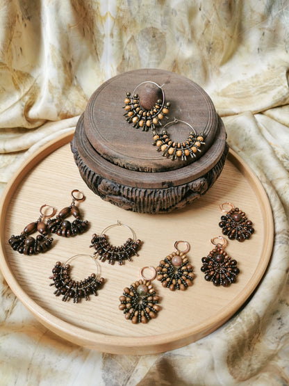 Jewelry set with earrings on a wooden tray and decorative box against a textured fabric background