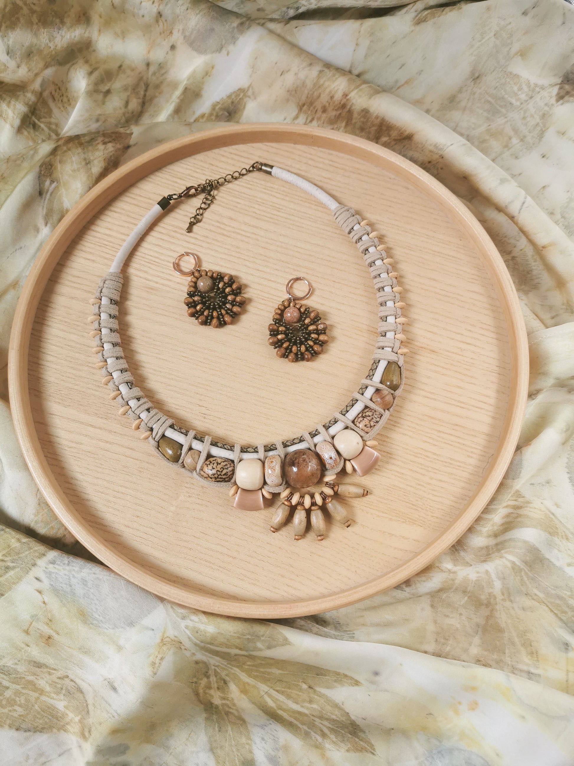 Necklace and earrings set on a wooden tray with a natural stone background