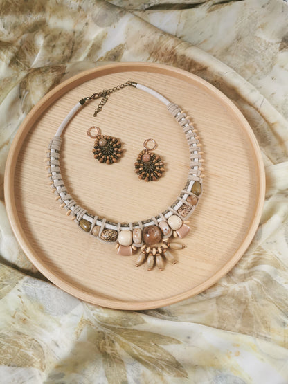 Necklace and earrings set on a wooden tray with a natural stone background