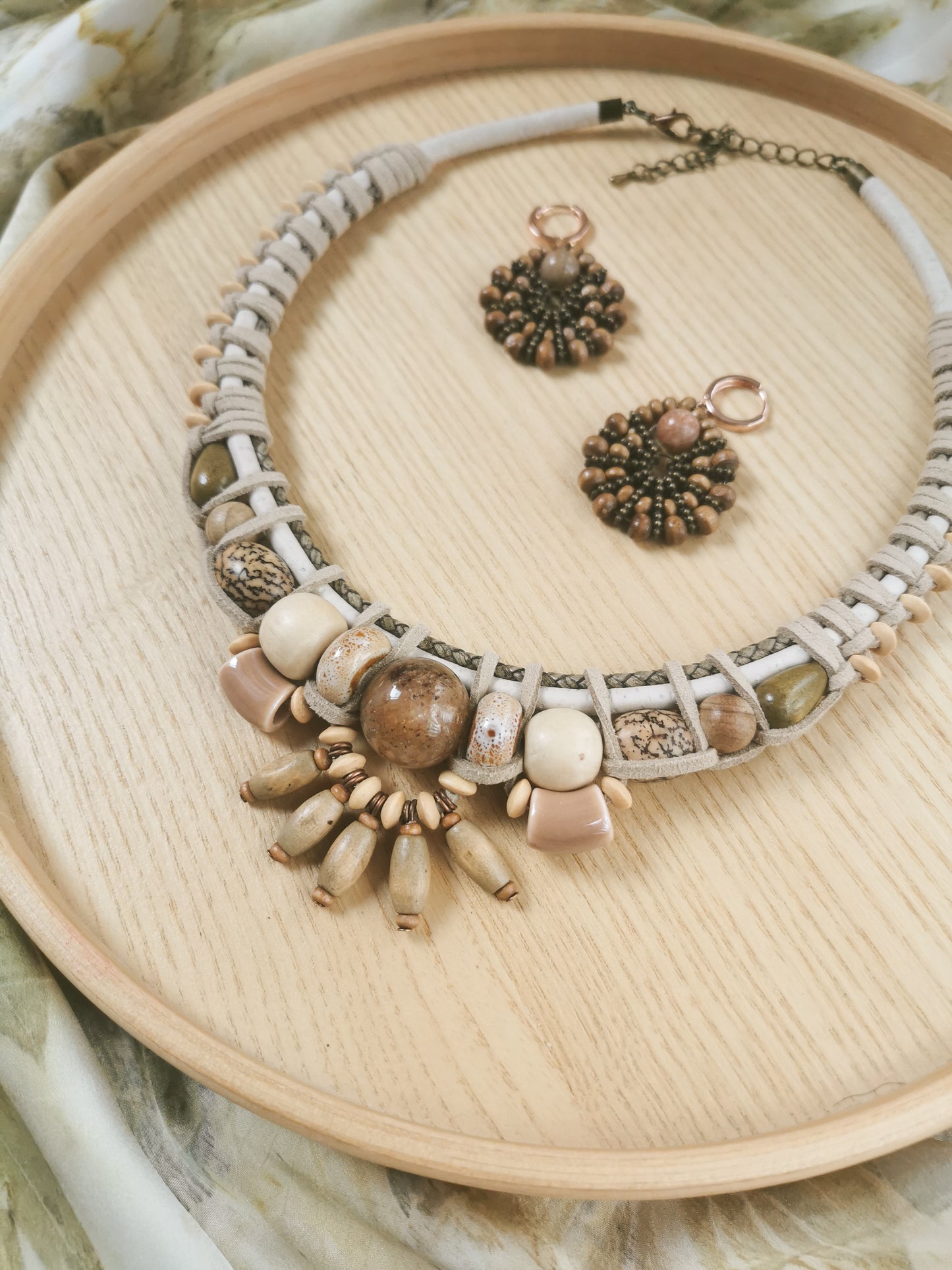 Necklace of various beads and earrings set on a wooden tray