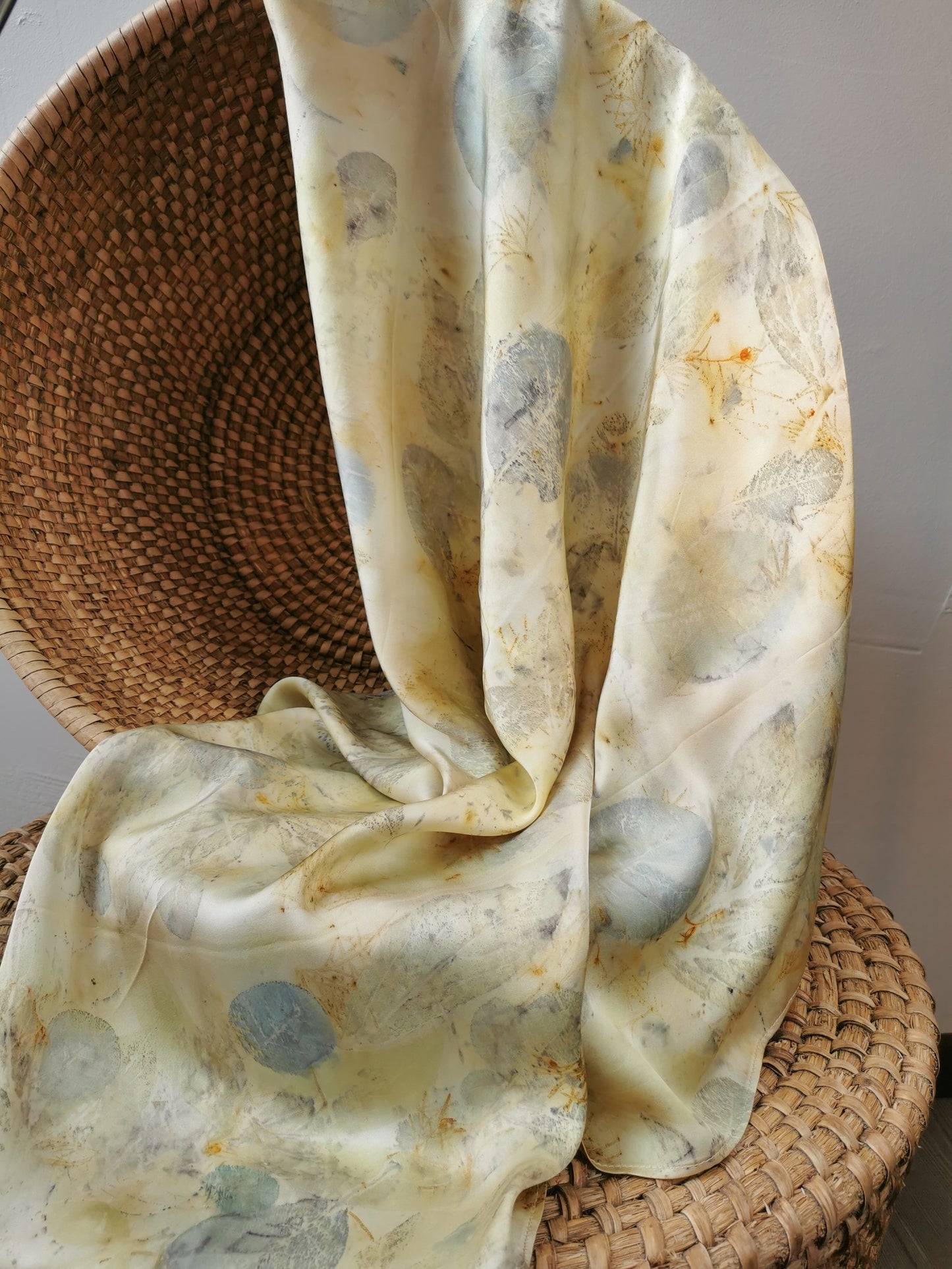 eco-printed citrus silk scarf draped over a woven basket on a neutral background
