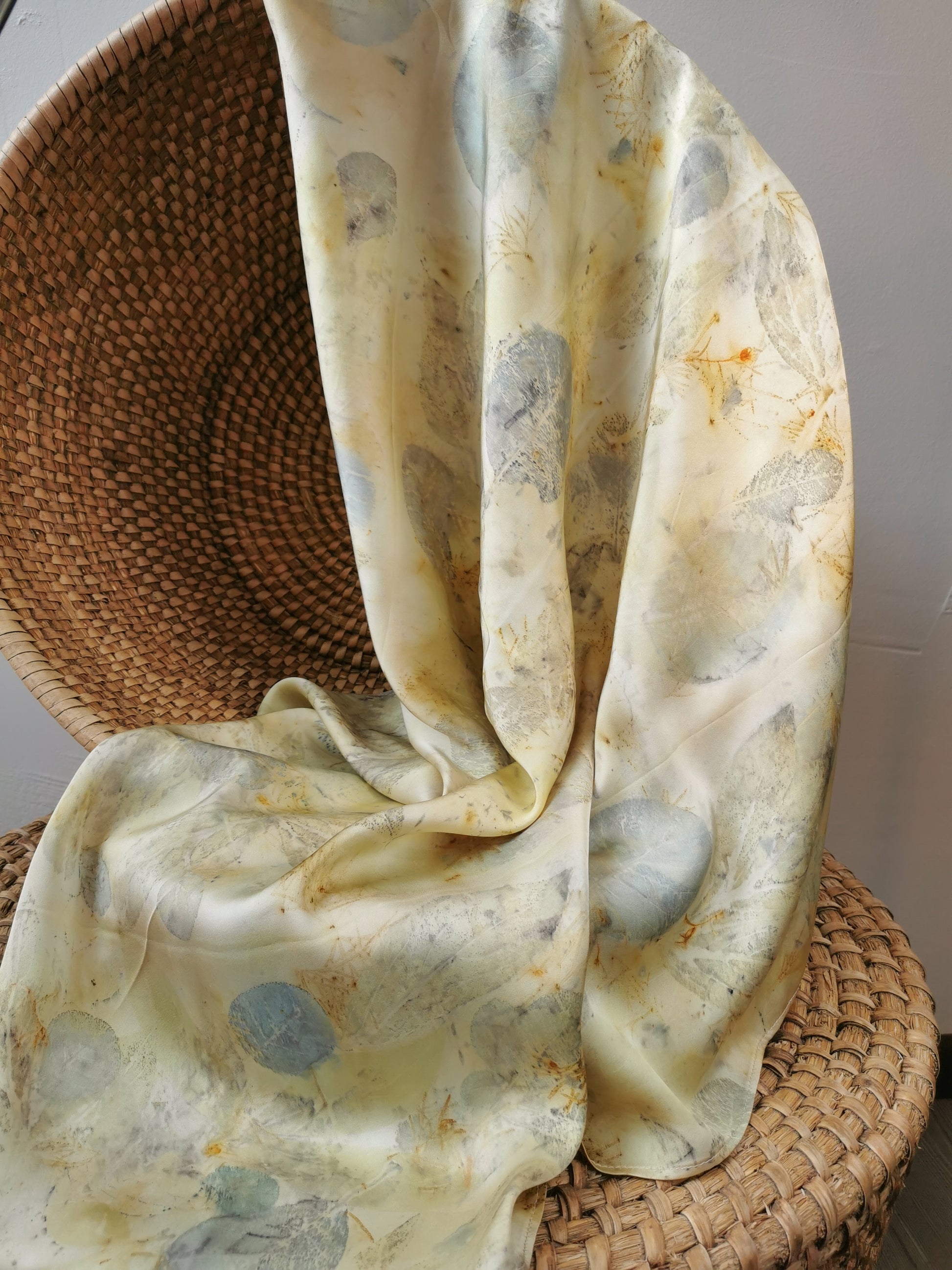 eco-printed citrus silk scarf draped over a woven basket on a neutral background