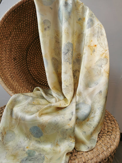 eco-printed citrus silk scarf draped over a woven basket on a neutral background