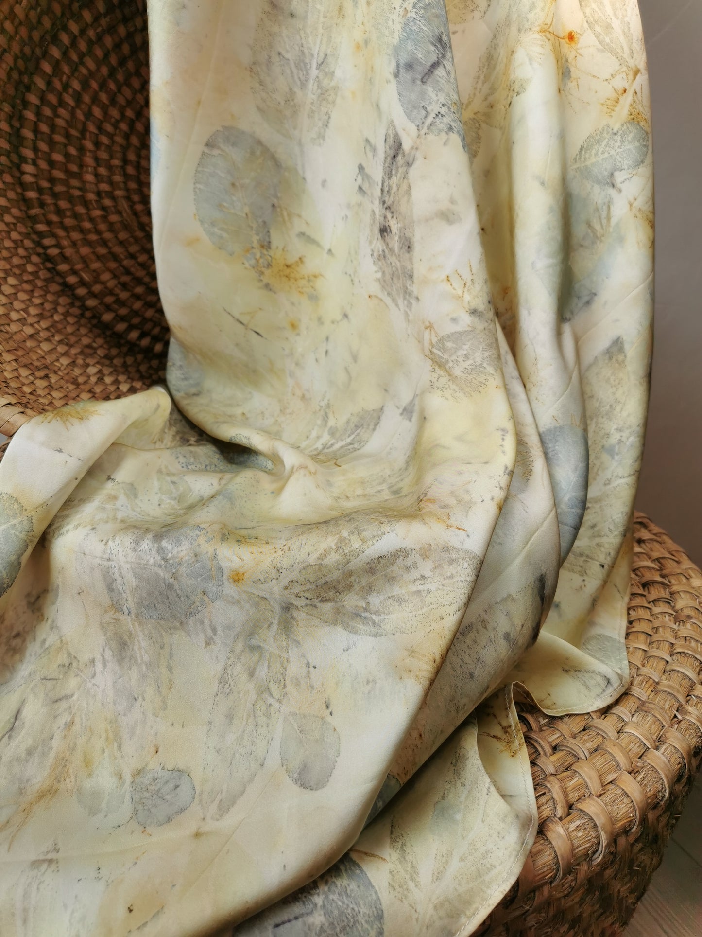 eco-printed citrus silk scarf with floral pattern draped over a woven basket
