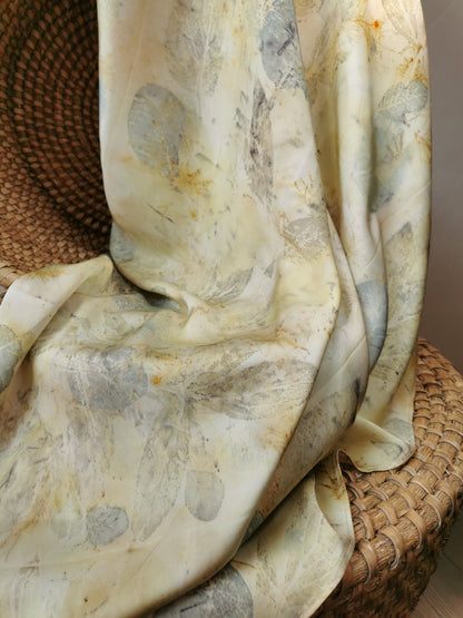 eco-printed citrus silk scarf with floral pattern draped over a woven basket