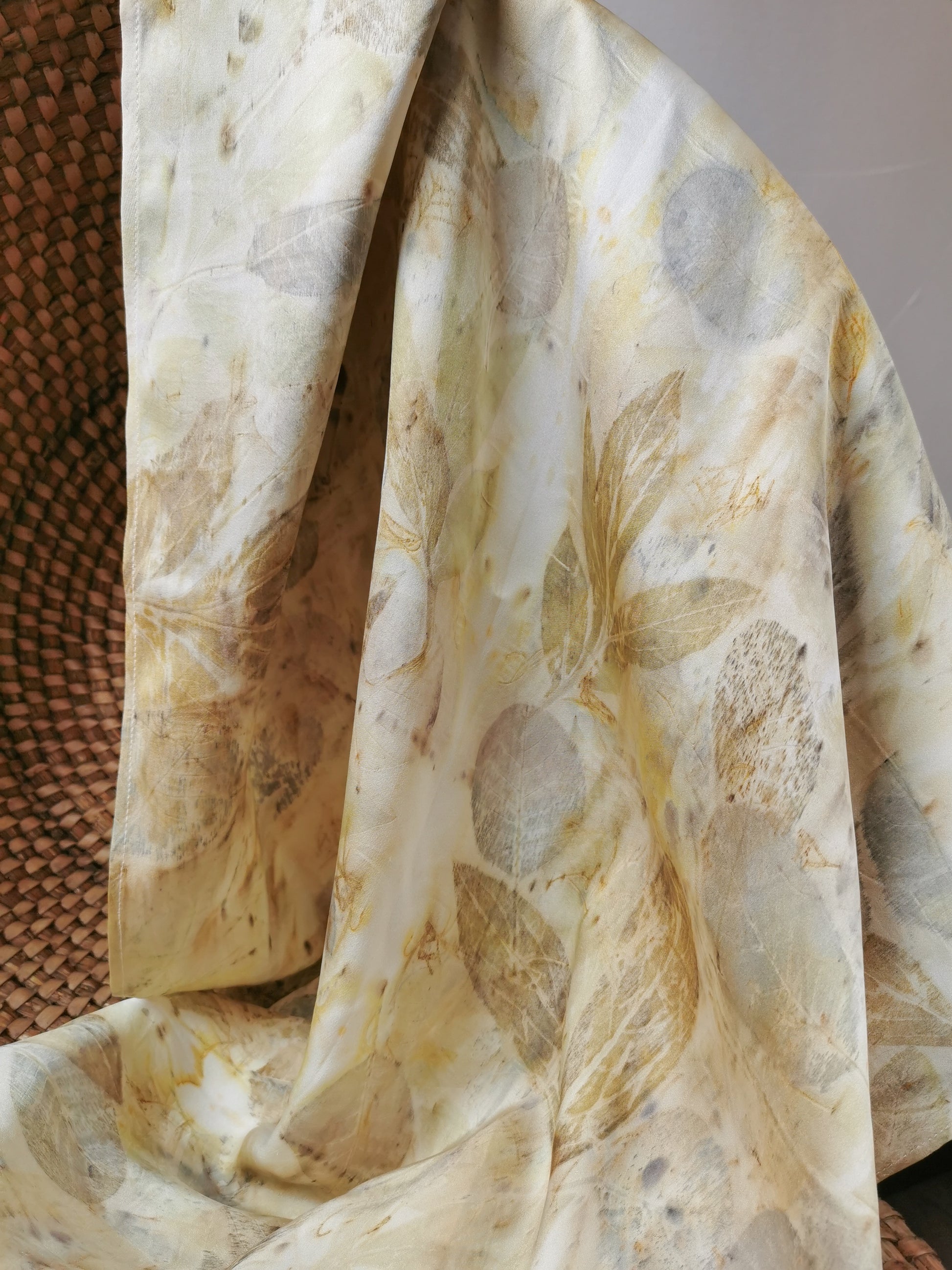 Close-up of eco-printed silk scarf with floral prints on a textured surface