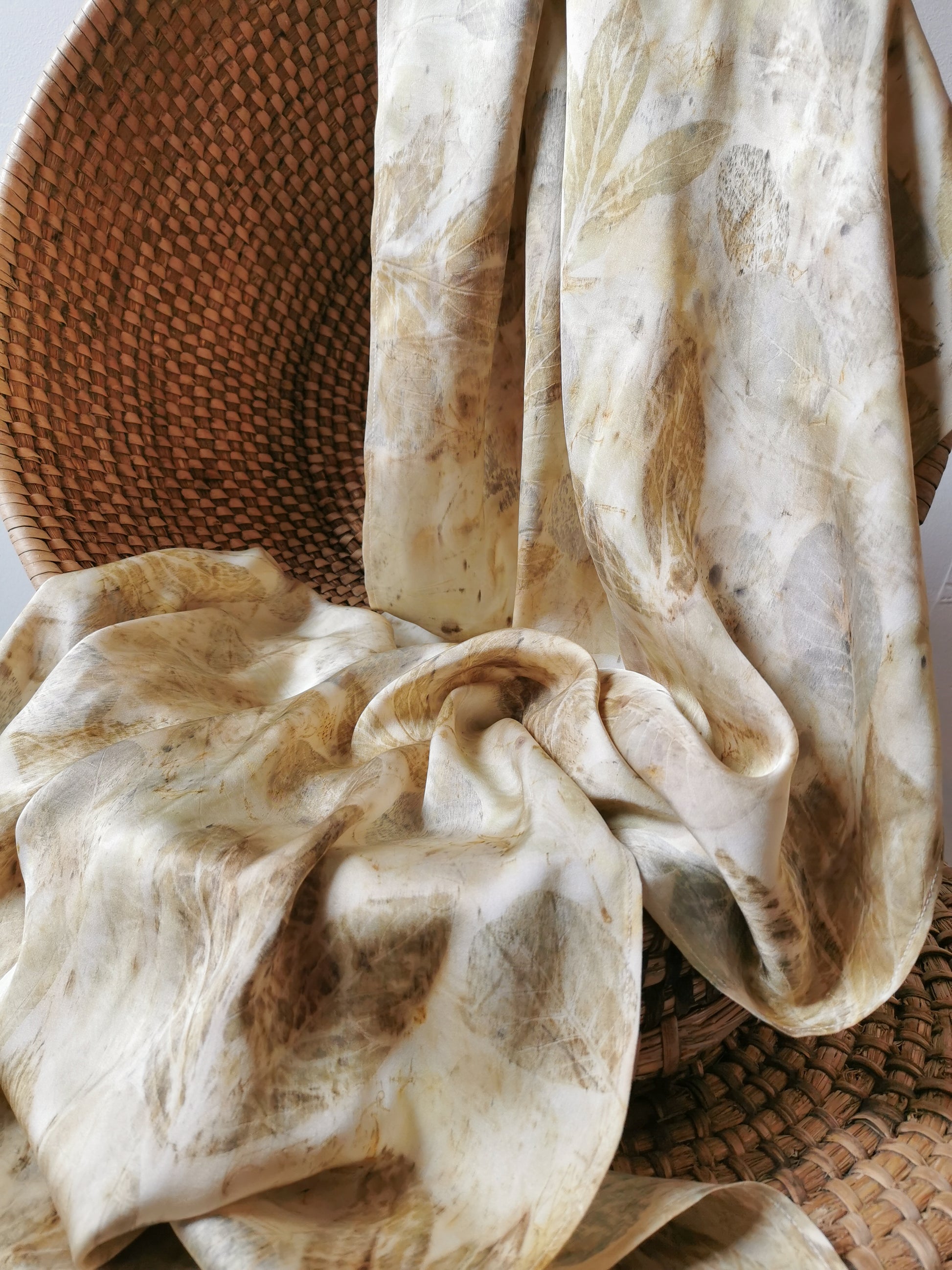 eco-printed silk scarf with floral prints draped over a woven basket