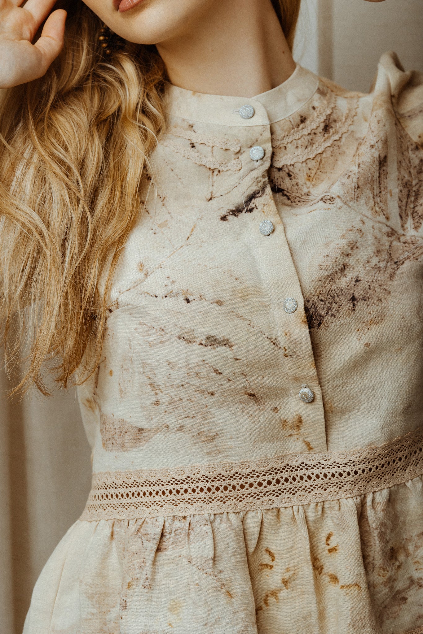 Close-up of a beige ecoprint linen blouse with lace with a blurred background