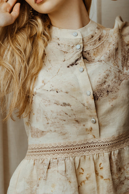 Close-up of a beige ecoprint linen blouse with lace with a blurred background