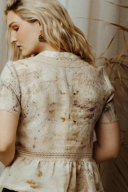 Woman wearing a ecoprint linen blouse with lace with a neutral background
