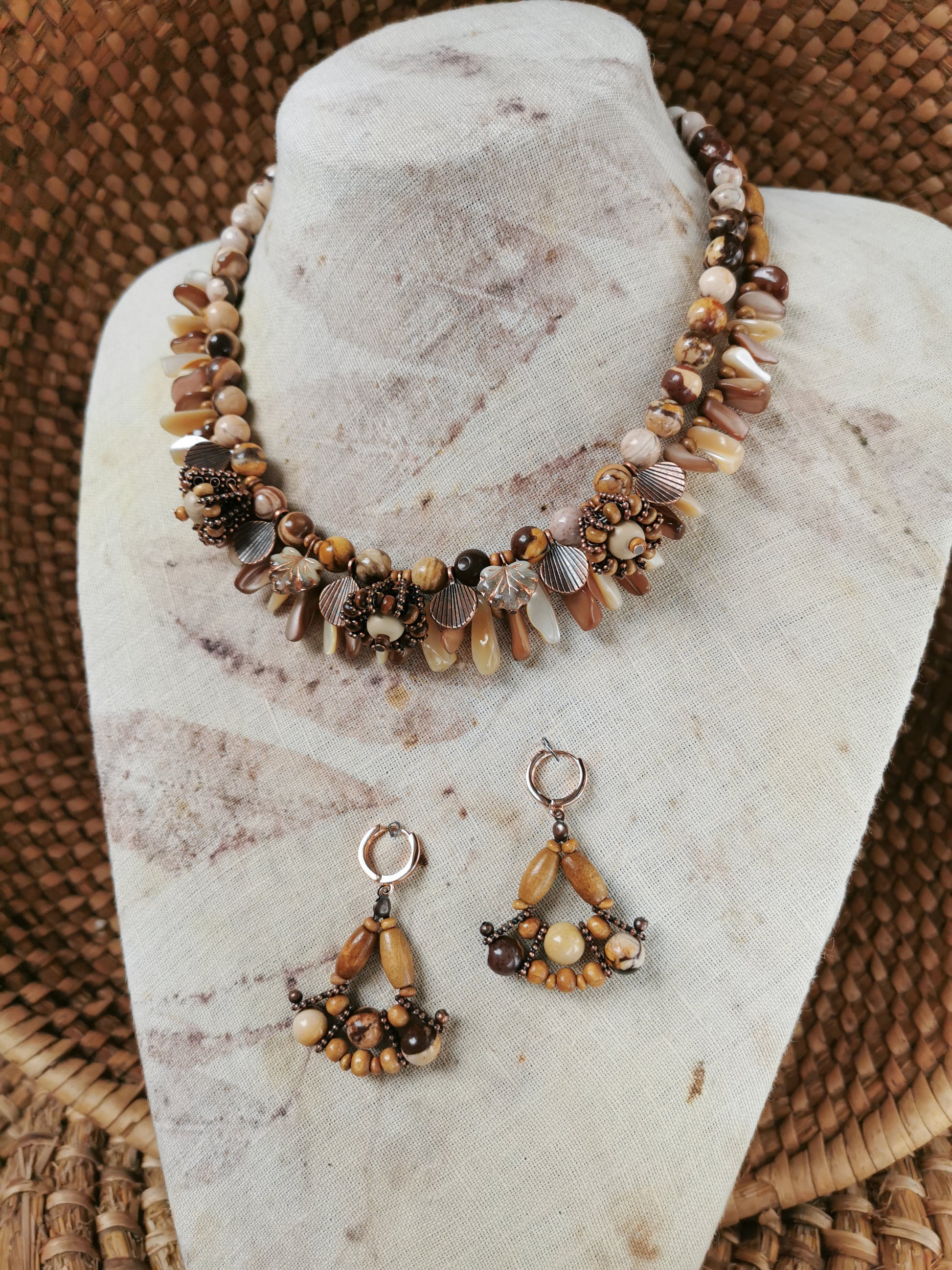 Necklace and earrings set on a marble stand with woven background
