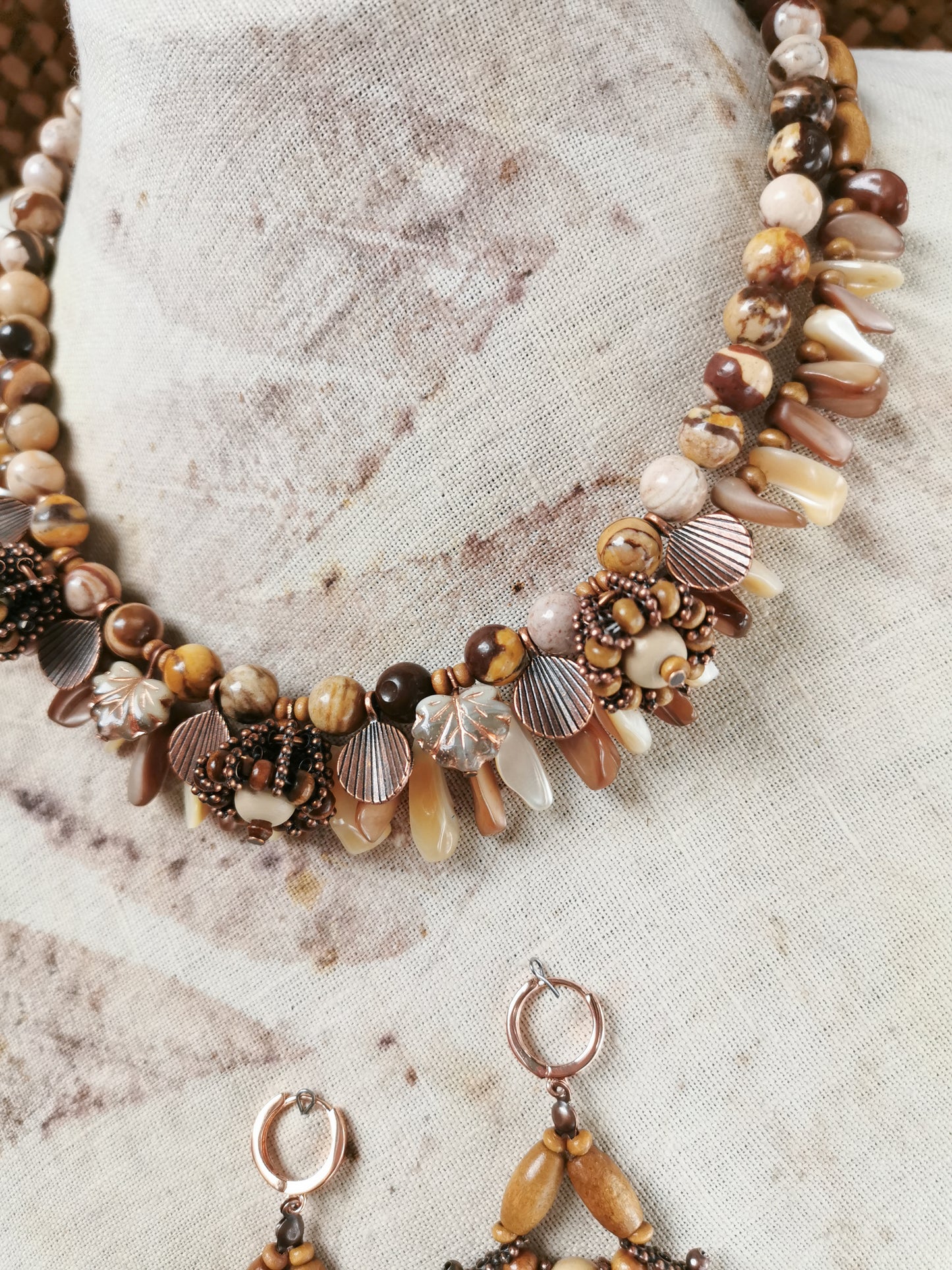 Necklace with seashell and bead details on a textured fabric background