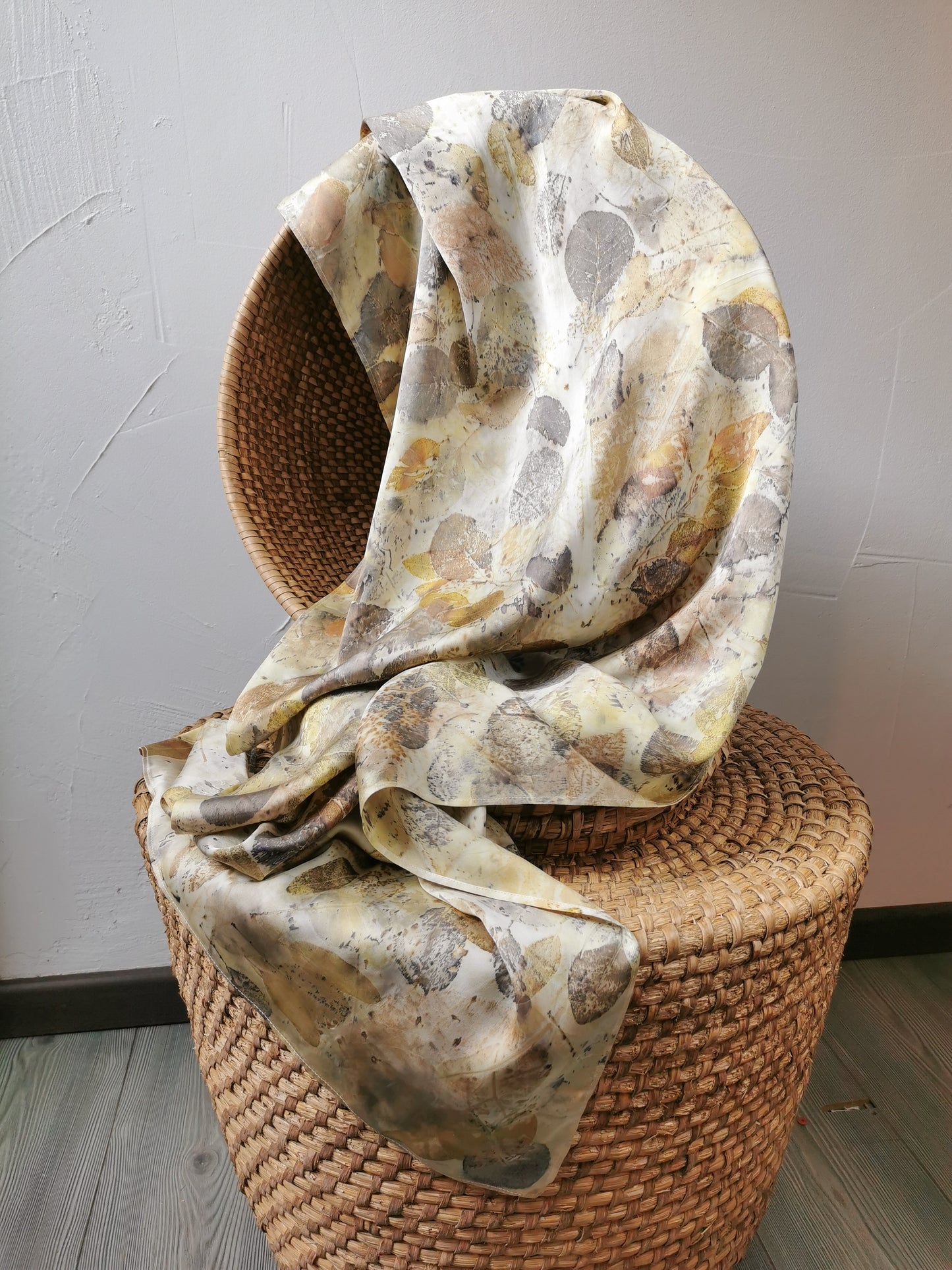 Floral-patterned scarf draped over a woven basket on a plain background